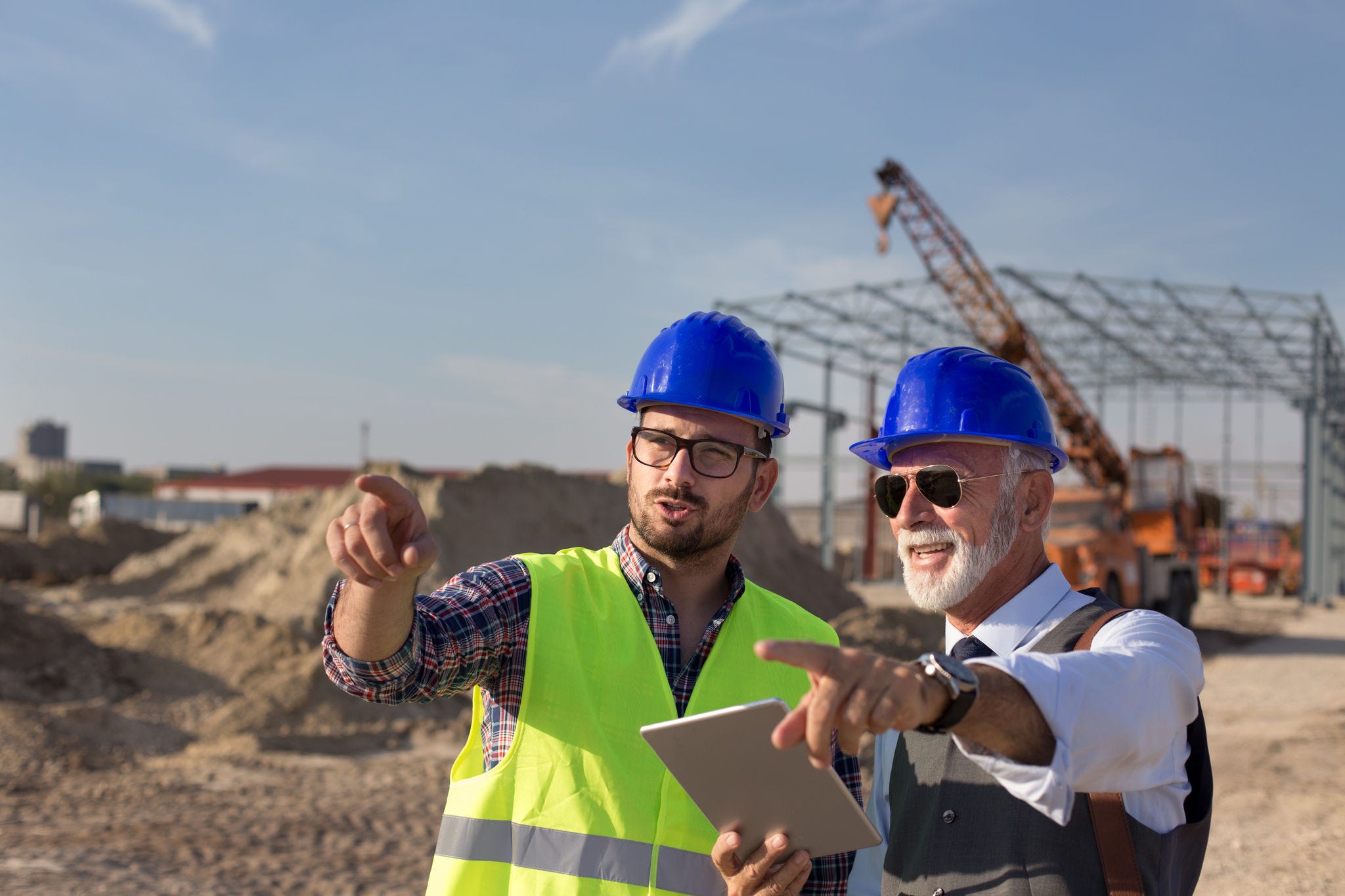 Two satisfied engineers talking at building site with construction structure in background; Shutterstock ID 1221071881; NP: Employability - Web policy issue page