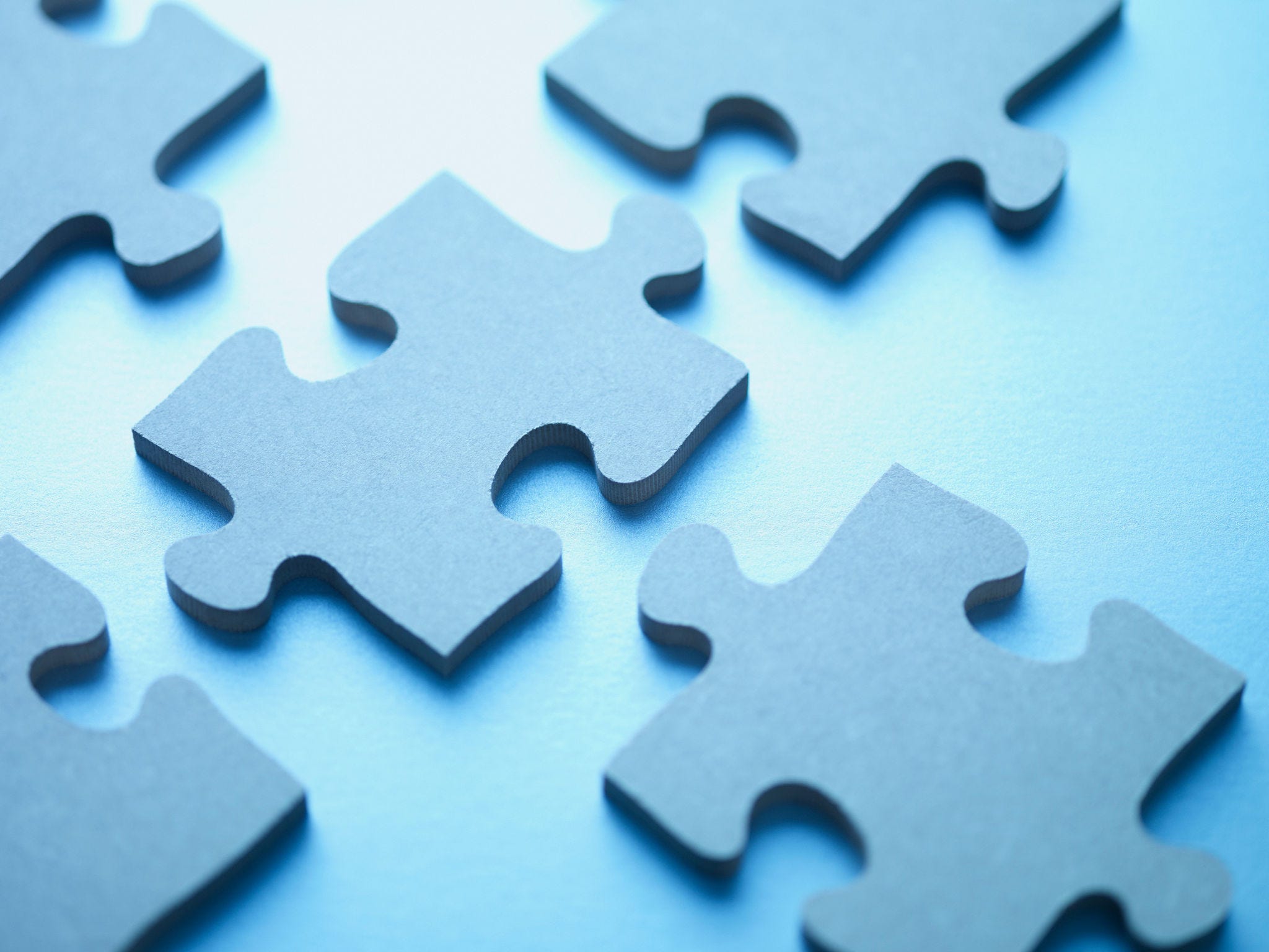 Blue jigsaw puzzle pieces on blue background ready to be placed. 